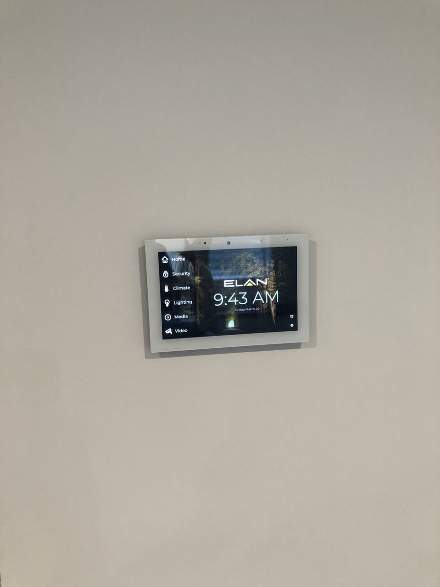 ELAN home automation touchscreen mounted on a wall, showing the control menu