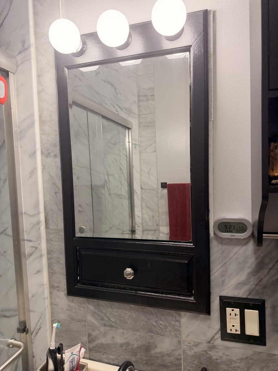 Before: old framed medicine-cabinet mirror with globe lights