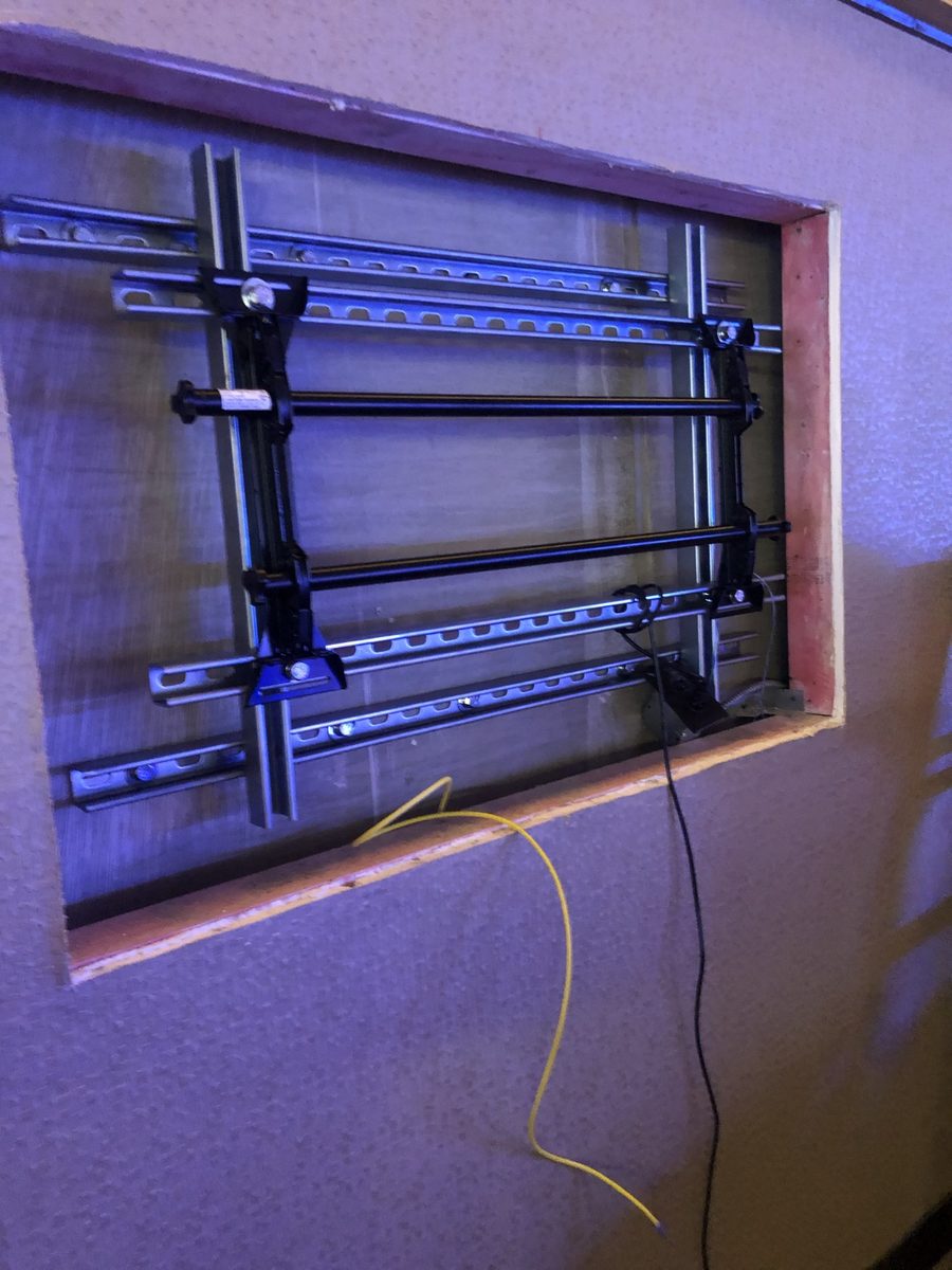 Before: TV mount bracket and wiring with a yellow cable in the recessed wall niche