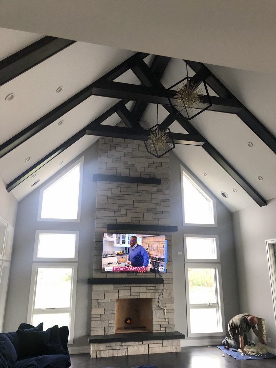 TV mounted on a tall stacked-stone fireplace in a great room with vaulted ceiling
